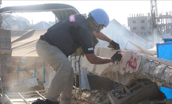 يقوم عضو في فريق دائرة الأمم المتحدة للإجراءات المتعلقة بالألغام (أونماس) بتحديد موقع لمخلفات الحرب المتفجرة بين المباني المدمرة.